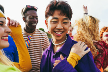 A group of youth wearing colorful makeup and clothing with grins on their faces.