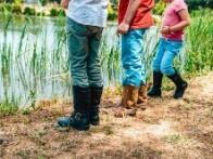 children facing a water source wearing boots