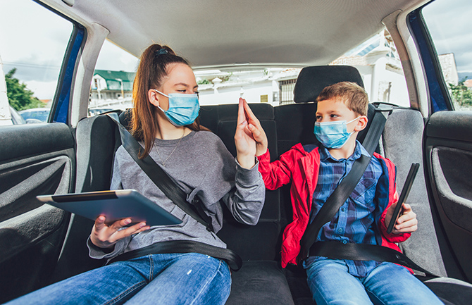 tennage year and young boy sitting in the backseat of a vehicle wearing seatbelts