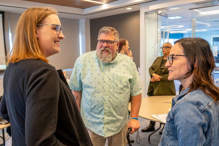Two women and a man standing in a circle talking