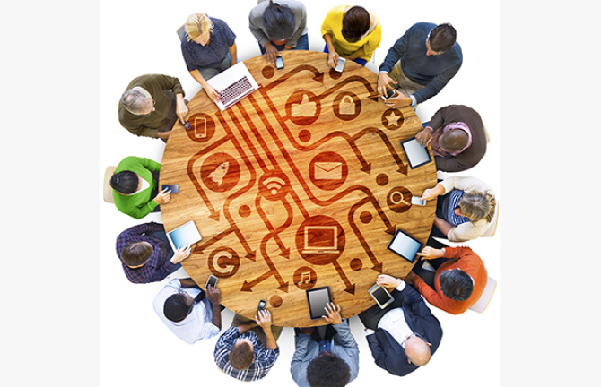 People around a round table with electronics in front of them and icons